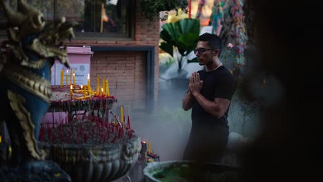 man praying at a temple in thailand