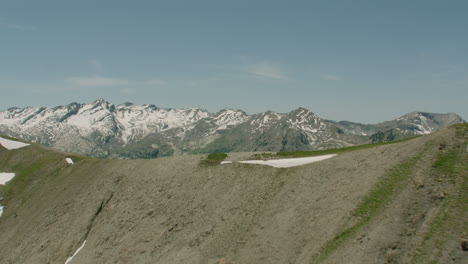 reveal of a mountain range with green land and snow covered tops