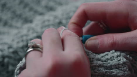 woman crochets a product from soft gray yarn - crochet process - close up