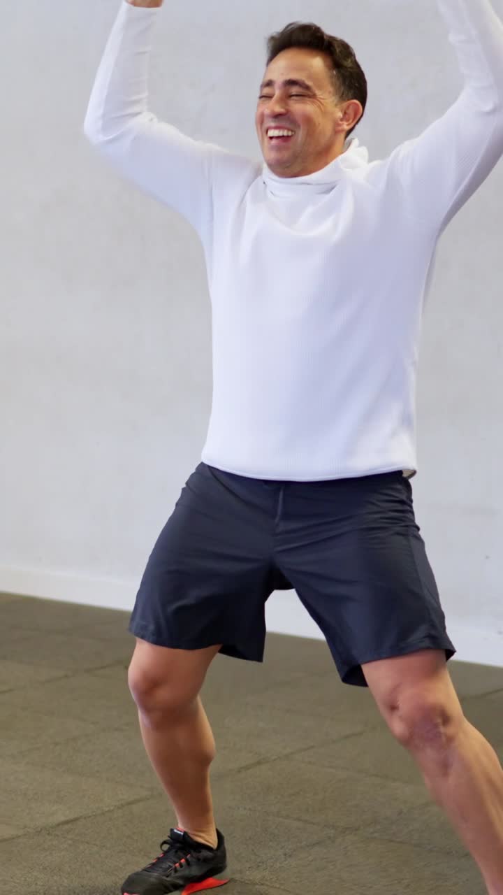 Uomo felice che fa esercizi di jumping jacks in palestra
