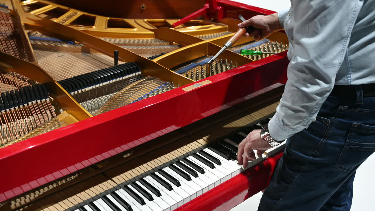 Primo piano di un uomo che sta riparando un pianoforte rosso
