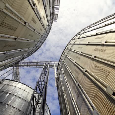 grain elevators under blue sky. huge metal grain storage tanks. silver containers. close-up. view from below.