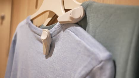 close up of two sweaters hanging on a clothes rack