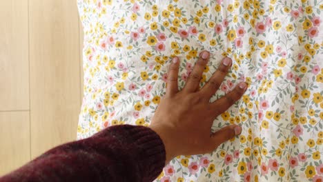 primer plano de una mano tocando una almohada de tela floral suave