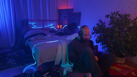 man relaxing in neon-lit bedroom