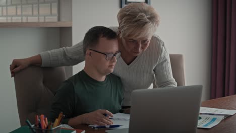 caucasian man with down syndrome learning with his mum at home.