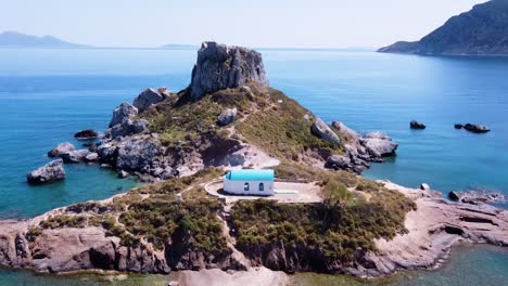 filmación cinematográfica de drones que revela una paradisíaca isla griega con una pequeña iglesia en ella