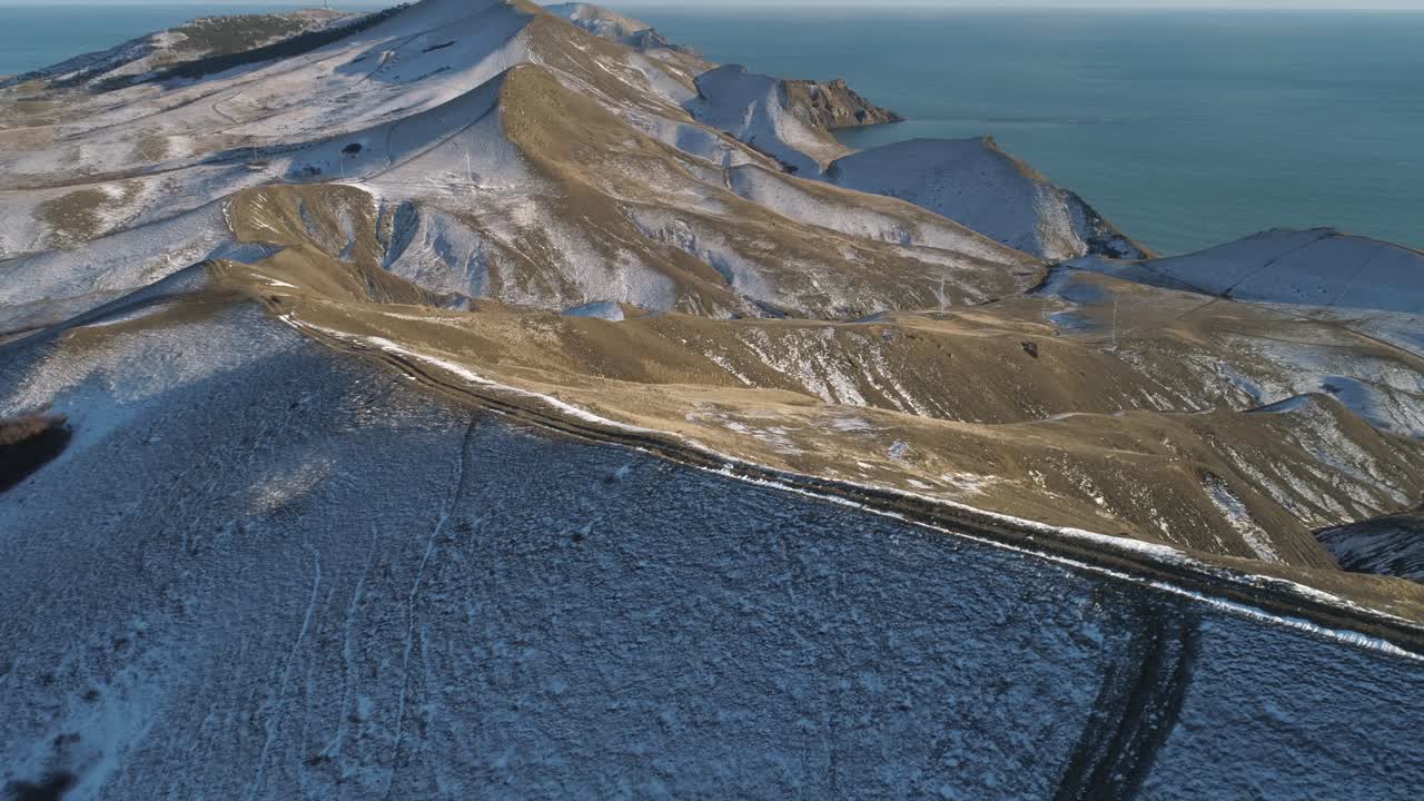 Luftfoto af sneklædte bjerge og kystlinje