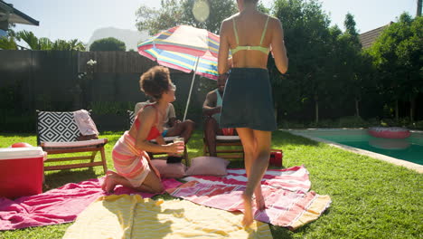diverse friends relaxing by pool, taking selfie under colorful umbrella on sunny day