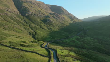 car heading up winding mountain road at sunrise. summer. kirkstone pass, lake district, cumbria, uk