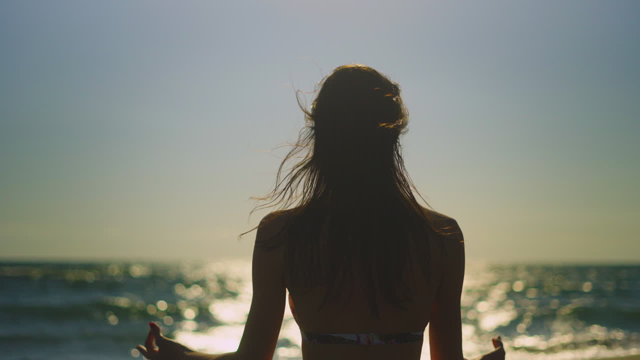 해가 지는 동안 해변 에서 명상 하는 여자