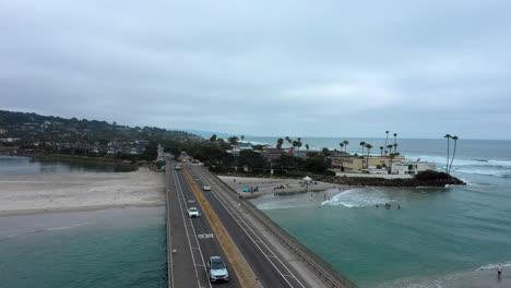 Cars-Driving-On-Small-Bridge-Between-Two-Beaches,-River-Merging-To-Ocean-Of-Del-Mar,-San-Diego,-In-California,-USA---static-shot