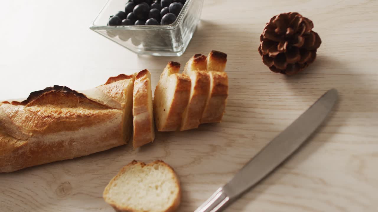 Video of baguette, bluberries and pine cone on a wooden surface