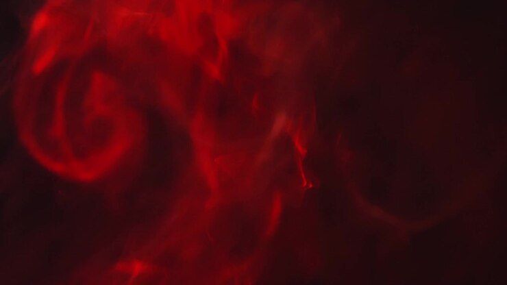 Close Up Of Red Smoke From Candle Or Incense Drifting Across Frame Against Black Background