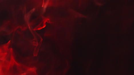 close up of red smoke from candle or incense drifting across frame against black background