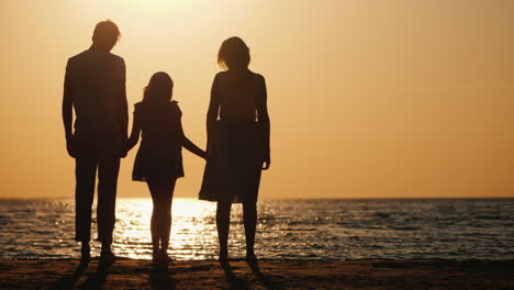 A-Young-Family-With-A-Child-Cuddles-And-Looks-Forward-To-The-Sunset-Over-The-Sea-Good-Time-Together-