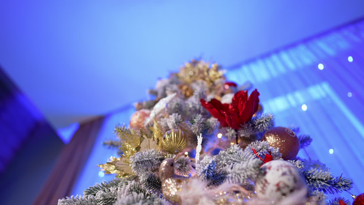 Beautiful decoration of the Christmas tree. Low angle view at the colorful ornaments on the snowy tree. Close up.