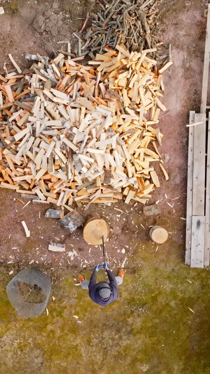 Aerial portrait above a man chopping firewood with an axe, springtime in Finland