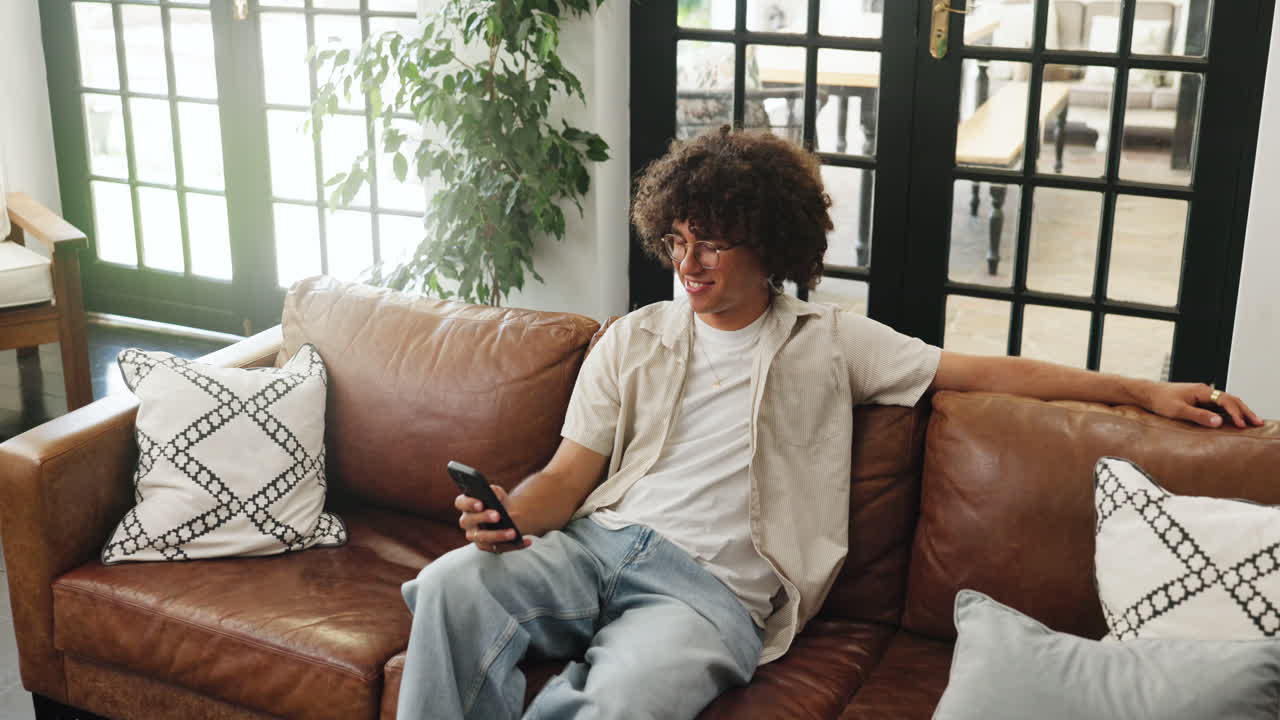 Giovane uomo che si rilassa sul divano mentre usa lo smartphone