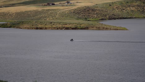 Dos-Personas-En-Una-Moto-De-Agua-Cruzando-Un-Lago