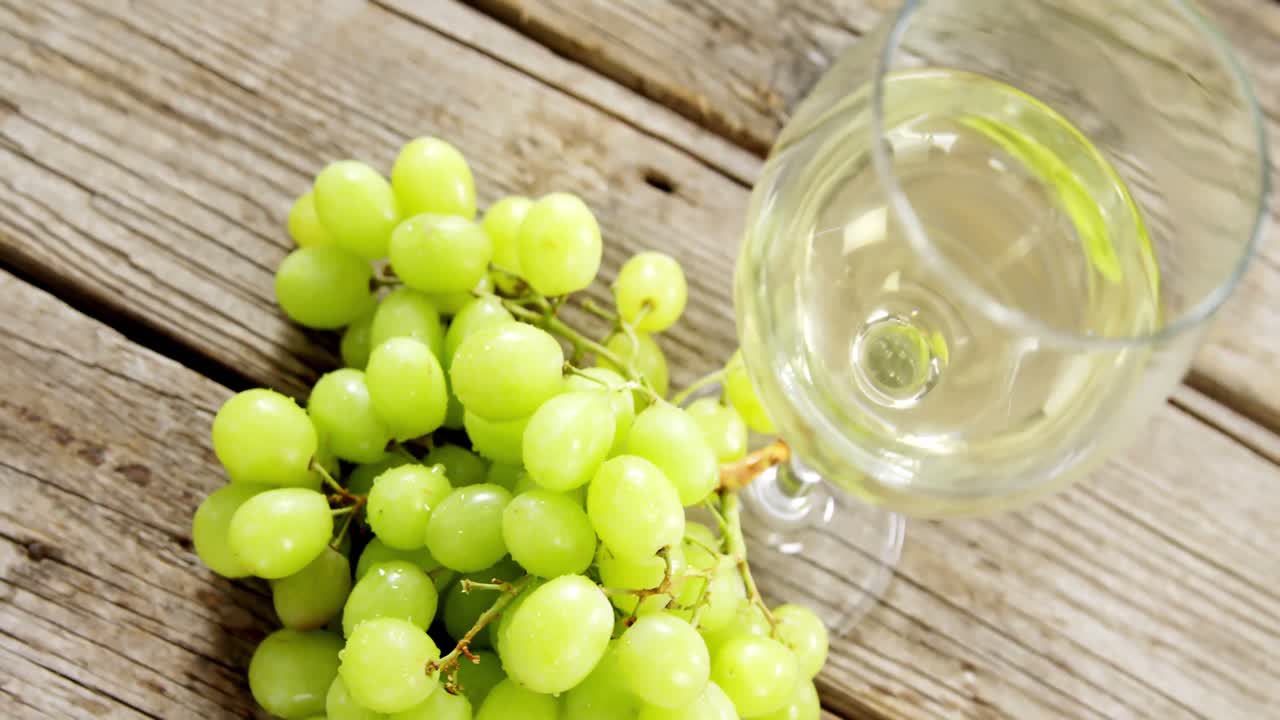 uvas y vino blanco en una tabla de madera