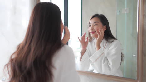 While-looking-in-a-mirror,-a-woman-examins-her-healthy-skin