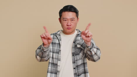 frightened asian man closing mouth with hands refusing to tell terrible secret unbelievable truth