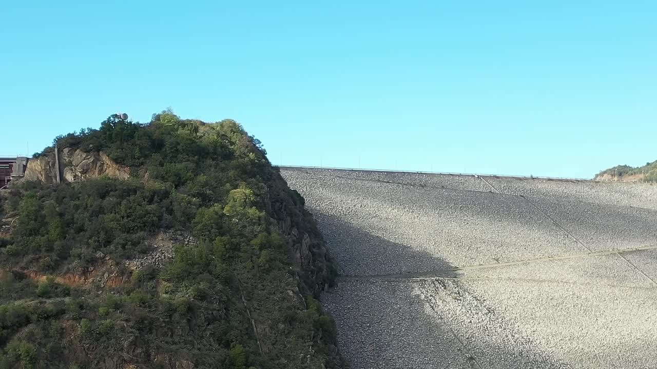 El Lago Colbún en Chile muestra una colina empinada y un cielo despejado.