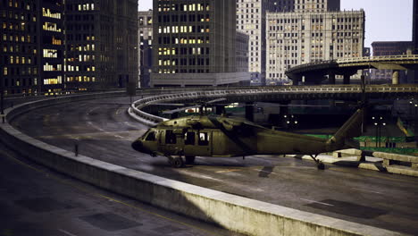 helicopter parked on a city overpass with buildings in the background at night