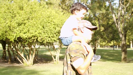 excited little boy riding dad's shoulders in park