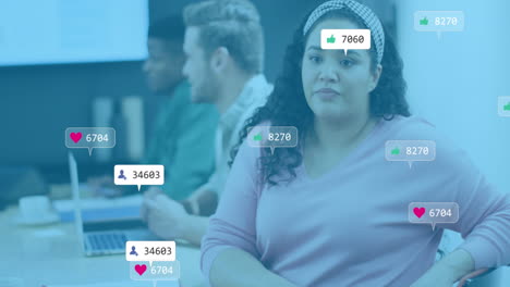 Animation-Von-Social-Media-Symbolen,-Die-Vor-Einer-Gemischtrassigen-Frau-Schweben,-Die-Im-Konferenzraum-Im-Büro-Sitzt