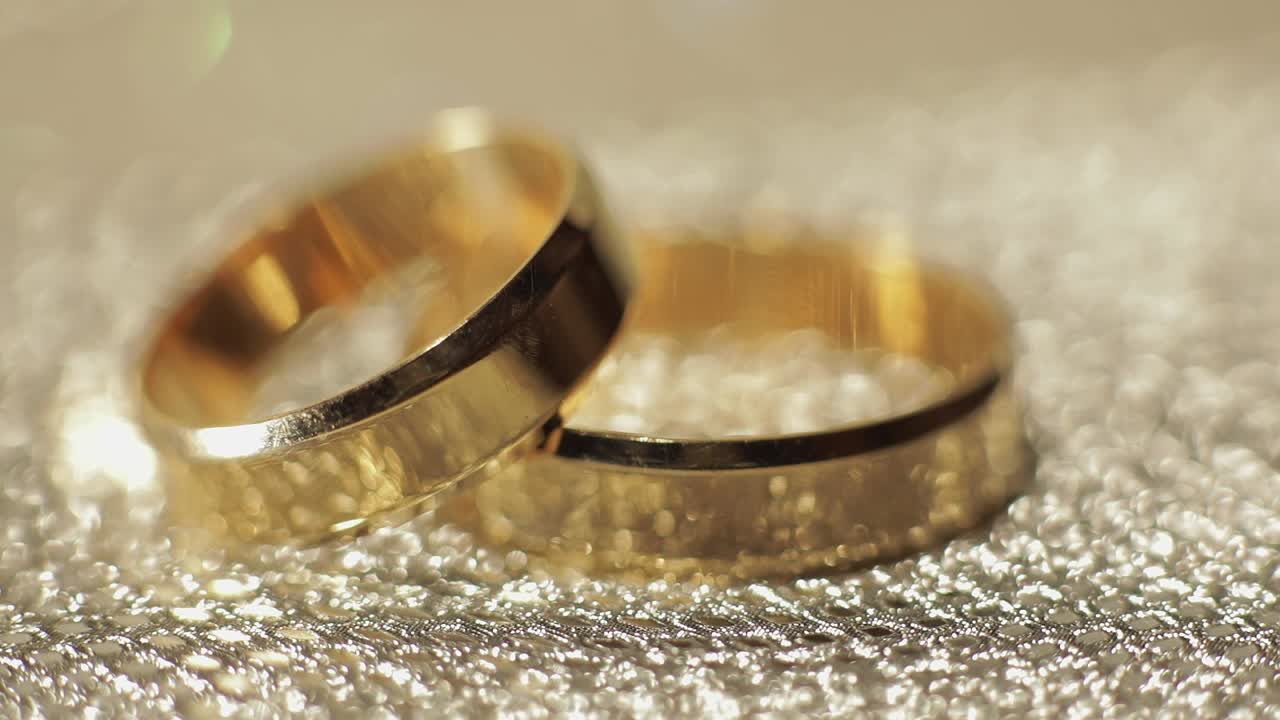 Wedding gols rings lying on shiny glossy surface. Shining with light. Close-up