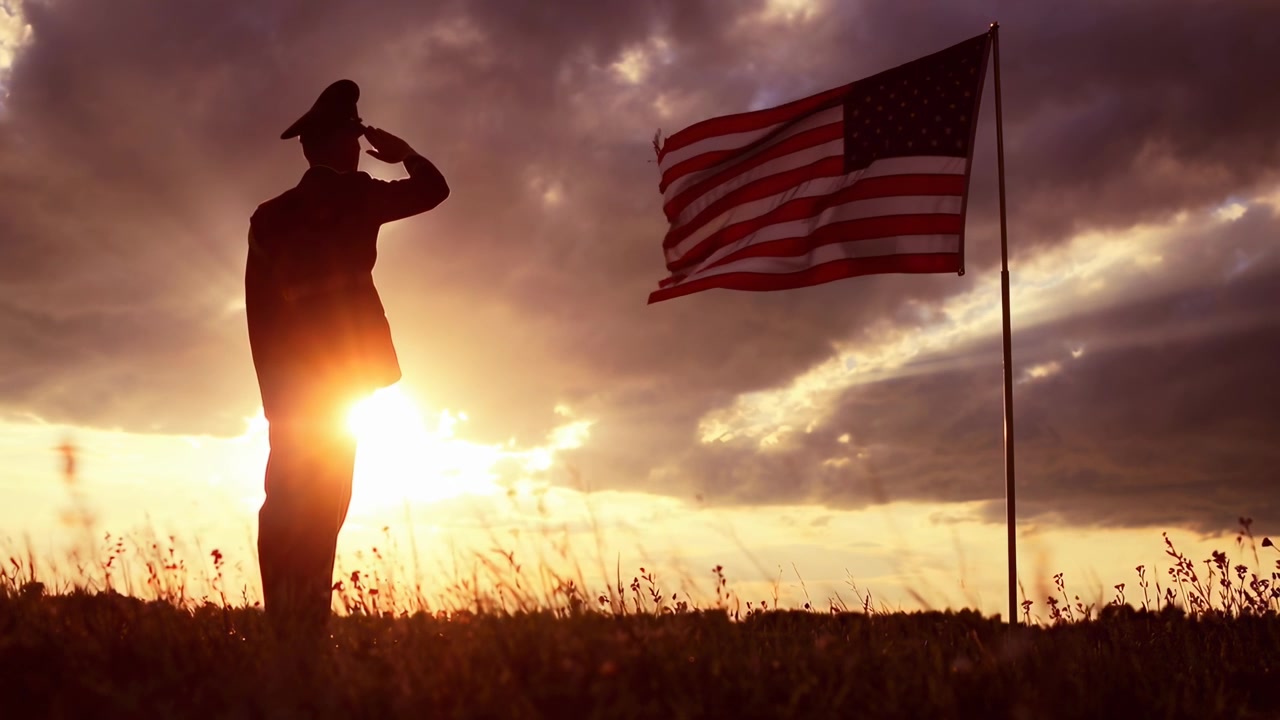 Militærofficer saluterer amerikansk flag ved solnedgang