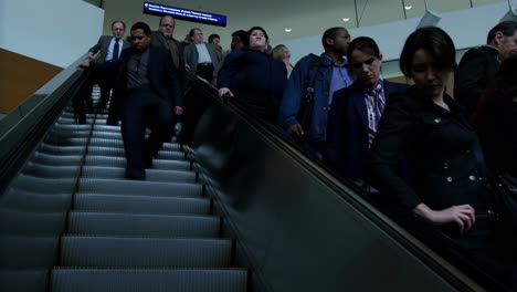 people riding an escalator in a busy public building