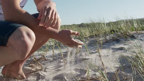 un homme accroupi sur la plage.