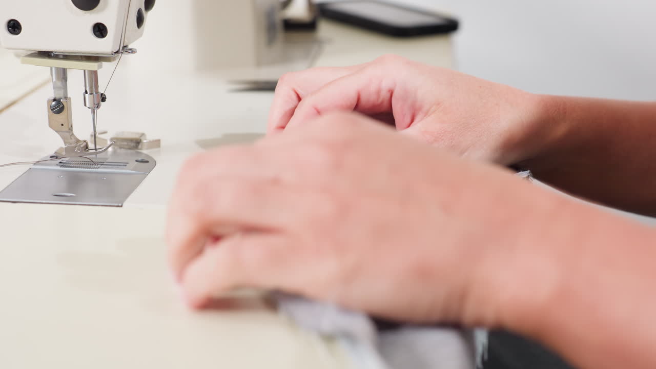 Designer with smiles on face lifting up design pattern she sewed with material, showing delight in final result, expressing creativity and satisfaction, proud of completed piece, radiating confidence