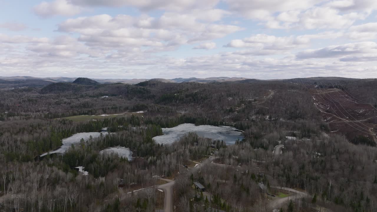 drone volando hacia el lago congelado con cielo nublado en el parque nacional de mont-tremblant, quebec, canadá