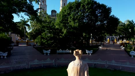 antena de madrugada ascendiendo sobre la fuente del parque sobre los árboles y sobre la catedral de san gervasio en valladolid, yucatán, méxico