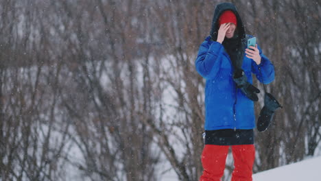 slow motion shot of a snowboarder using a smartphone while driving on a ski slope