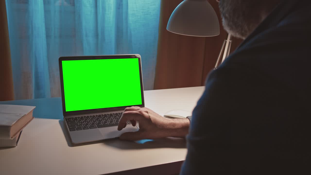 sobre el hombro de hombres trabajando en una computadora portátil moderna con una maqueta de pantalla verde. manos en el teclado.