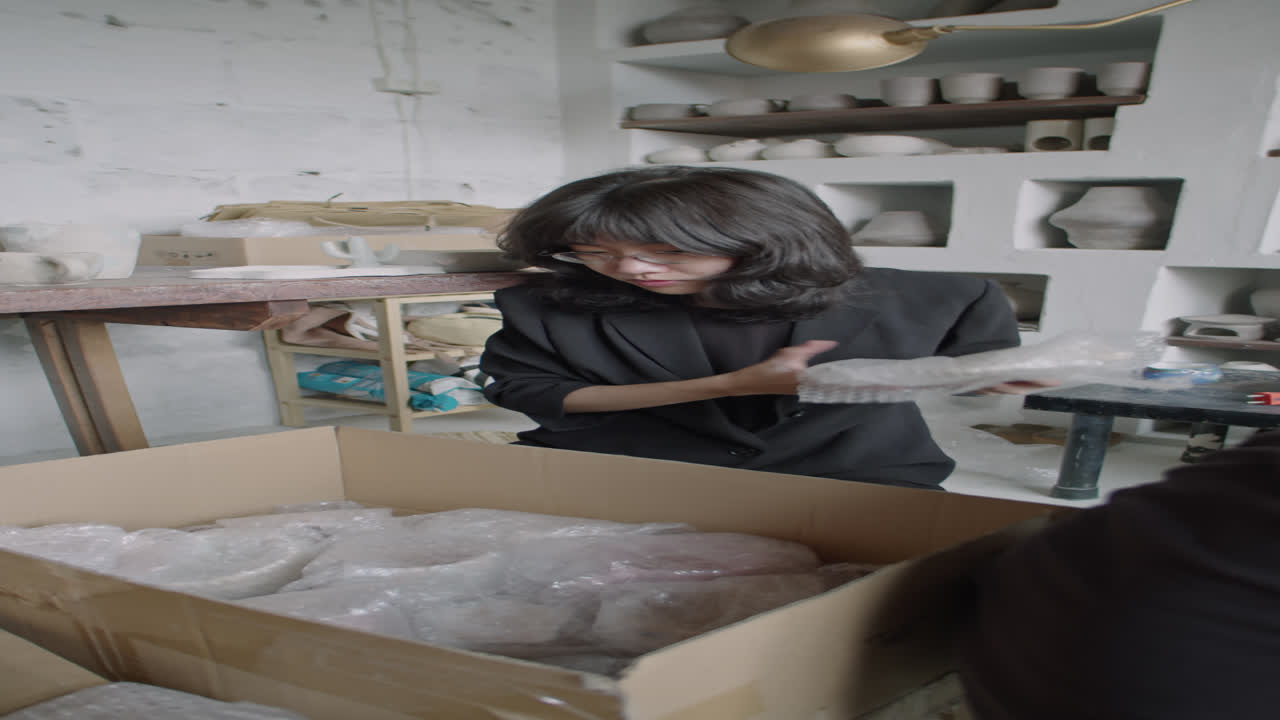 Female Potter Packing Ceramics into Boxes for Sale