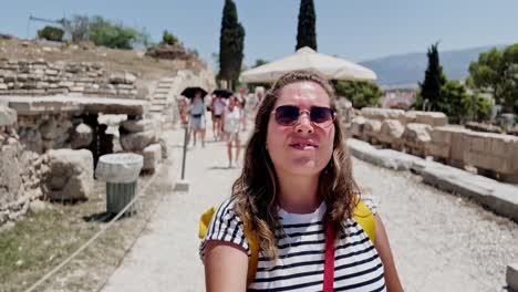 candid woman walking among historic ruins in athens, greece
