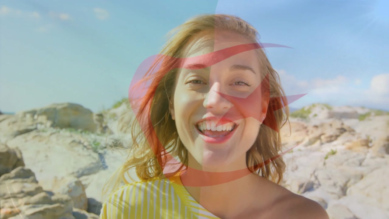 woman standing on rocky coastal shore, showcasing tech-themed red crescent star graphic overlay