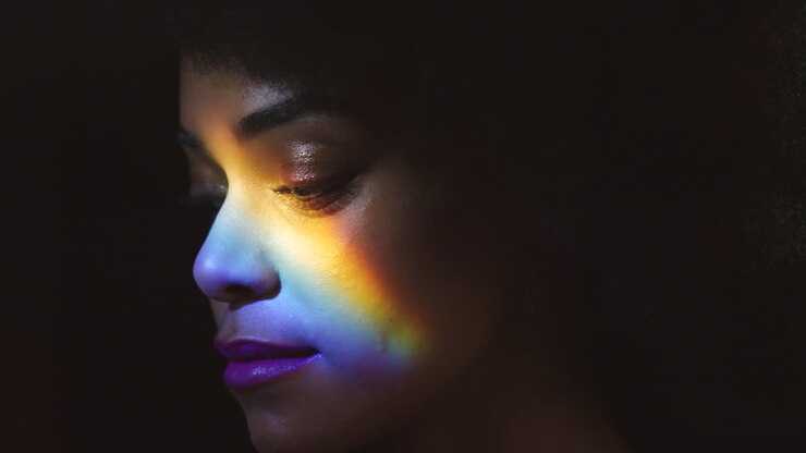 Arcobaleno, luce prismatica e volto di una donna nera