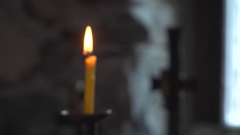 close-up of a burning candle and a cross in the background. bulgarian orthodox chapel. eastern orthodox church. racking focus. мystical.