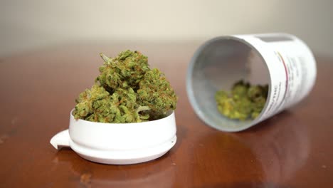 cannabis buds in a white container on a wooden table