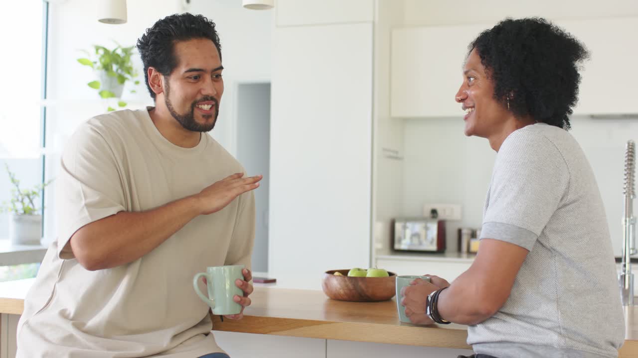 Vertical video: Starting to speak, left man gesturing with mint mug at home, catching up