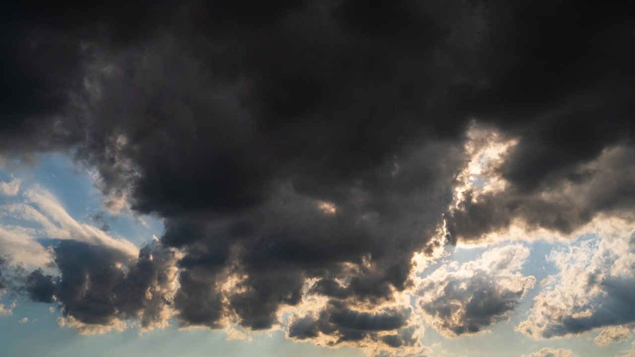 Mørke skyer letter, solstråler skinner igennem den bevægende himmel