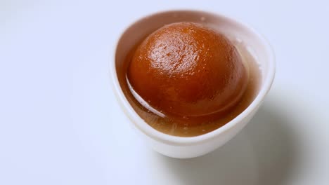 gulab jamun girando en un cuenco blanco ( dulce indio ) | postre
