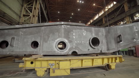 large metal part being transported on a cart in a factory